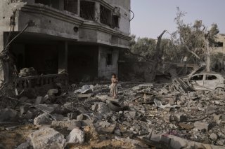 Une jeune fille se promène parmi les ruines, à Gaza. KEYSTONE/AP/Abdel Kareem Hana